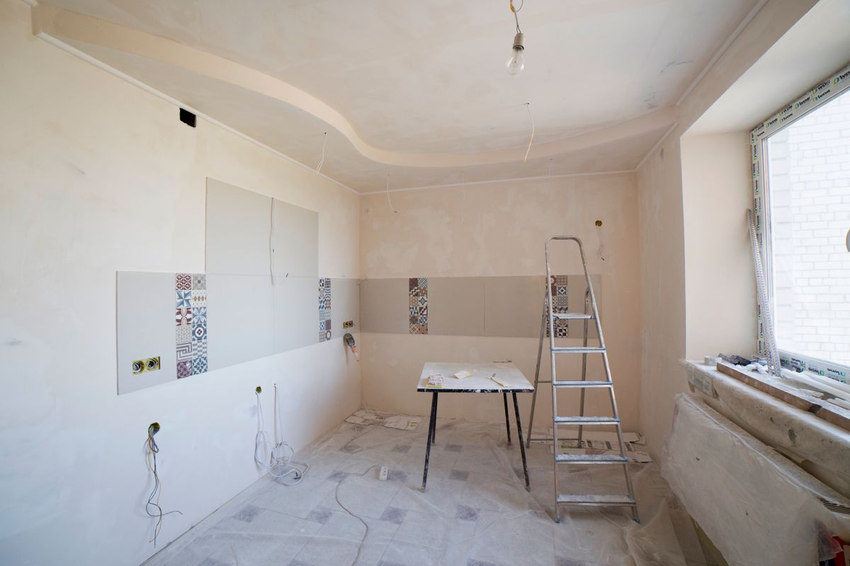 Kitchen being renovated with a ladder in the middle of the room and dust sheets protecting the floor