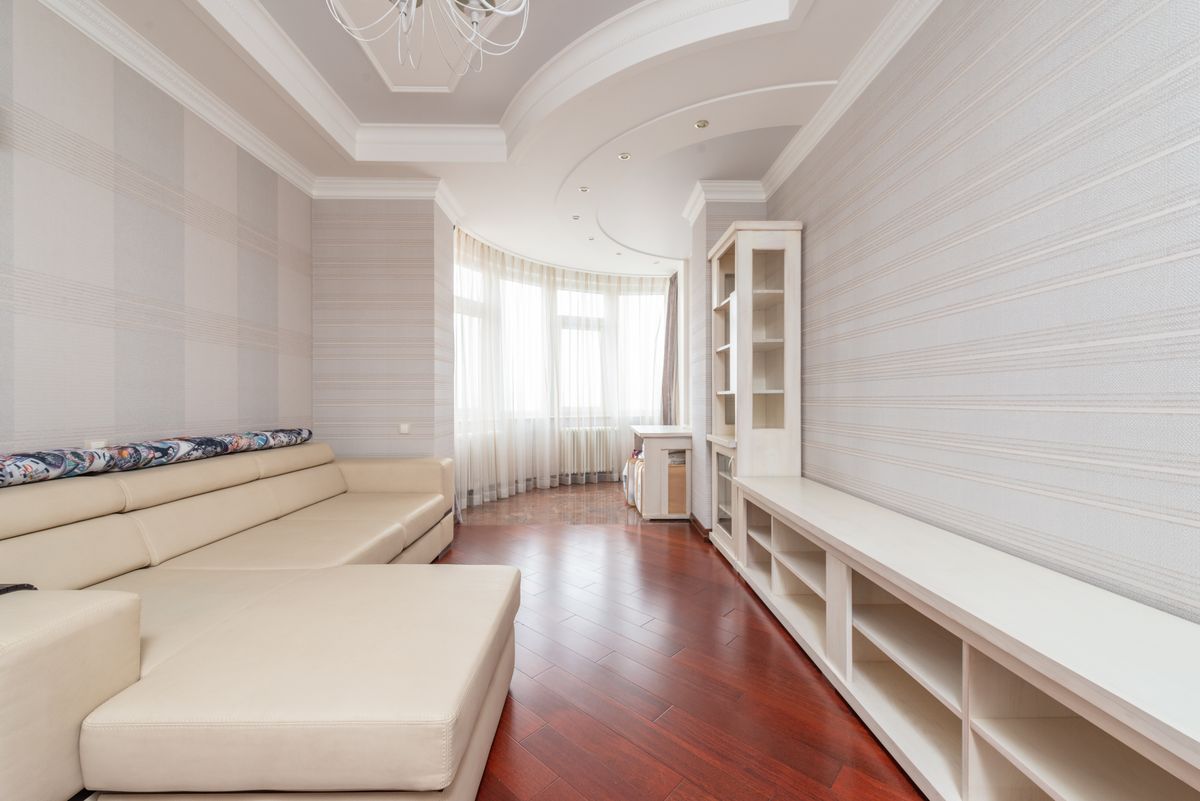 Sitting room with a smooth white multi-level ceiling, cove details, and built-in shelving along one wall